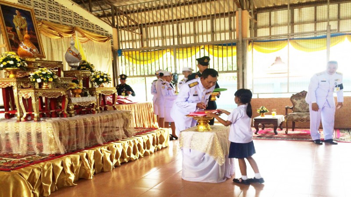 สมเด็จพระเจ้าอยู่หัว ทรงพระกรุณาโปรดเกล้าโปรดกระหม่อมให้ องคมนตรี เชิญอุปกรณ์การเรียนเครื่องเขียนพระราชทานไปมอบแก่ นักเรียน ร.ร.ตำหนักเพนียด