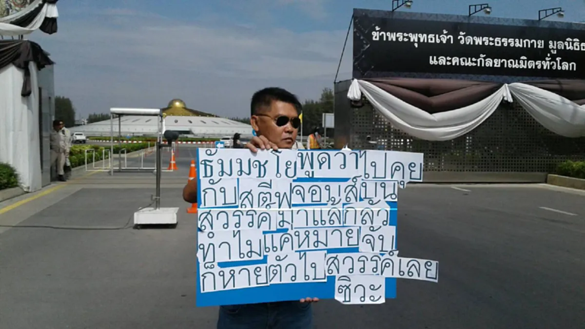 กลัวทำไมแค่หมายจับ!!? "หนุ่มรปภ." เดินชูป้ายท้าทาย "ธัมมชโย" หน้าวัดพระธรรมกาย พร้อมลั่นประโยคสุดจี๊ด สะเทือนถึงสาวก!! 