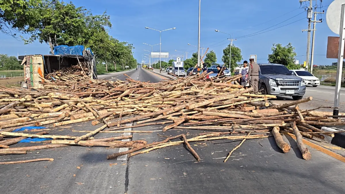 ระทึกแยกไฟแดงสุพรรณฯ รถพ่วงบรรทุกไม้ยูคาพลิกคว่ำ กระเด็นใส่รถ